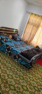 1 cama con edredón azul y ventana en magray guest house en Gulmarg
