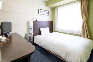 Habitación de hotel con cama y escritorio con ordenador en Comfort Hotel Niigata en Niigata