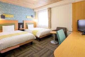 a hotel room with two beds and a flat screen tv at Comfort Hotel Kokura in Kitakyushu