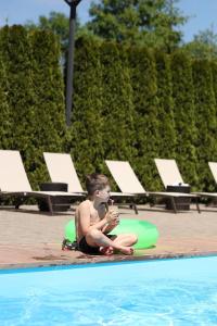 um rapaz sentado no chão ao lado de uma piscina em СПА-Готель "RESPECT" em Skhidnitsa