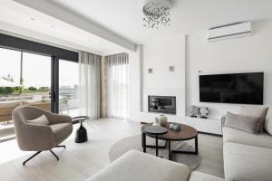 a white living room with a couch and a chair at Black Lotus Pool Villa, Afitos #FeelsLikeHome in Afitos
