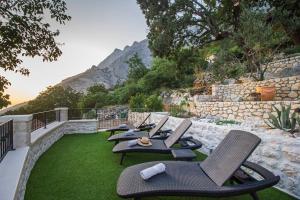 a row of chairs sitting on top of a lawn at Incredibly beautiful Stone House Villa Lota - Makarska Exklusiv in Bast