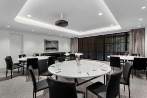 Adina Apartment Hotel Melbourne Southbank في ملبورن: قاعة اجتماعات مع طاولات وكراسي ونافذة كبيرة