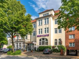 een groot wit gebouw met een stokstaartje erop bij Mercure Hotel Luebeck City Center in Lübeck