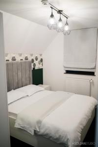 - une chambre dotée d'un lit avec des draps blancs et des lumières dans l'établissement La Codrii Cajvanei, 