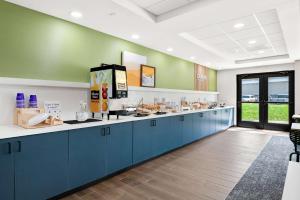 a kitchen with blue cabinets and green walls at Spark by Hilton Lancaster Dutch Country in Lancaster