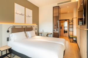 a bedroom with a large white bed in a room at Leonardo Hotel San Sebastián in Donostia-San Sebastián