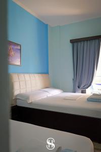a bedroom with two beds and a blue wall at Sala's Boutique Hotel in Sarandë