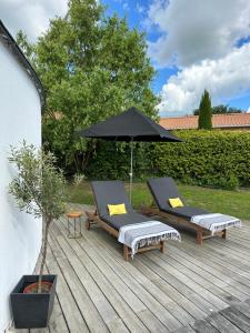 2 chaises longues et un parasol sur une terrasse en bois dans l'établissement Villa K Maison archi avec piscine 15 mn PUY du FOU, à Cholet