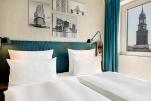 a bedroom with two white beds and a window at Motel One Hamburg am Michel in Hamburg