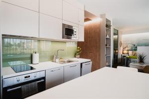 una cocina con armarios blancos y fregadero en Butique Apartman Grand en Balatonlelle