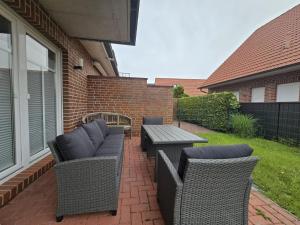 a patio with wicker chairs and a table on a house at Ferienwohnung KüstenSAND in Norden