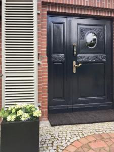 a black door on a brick house with flowers at Ferienhaus Turm360, FeWo Vermittlung Nordsee, C Hüppeler in Varel