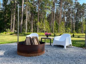 una hoguera con 2 sillas y una mesa con troncos en Mustika Mirror minivilla saunaga, en Kärdla