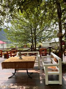 einen Tisch und Stühle auf einer Terrasse unter einem Baum in der Unterkunft Ioska's House in Mestia