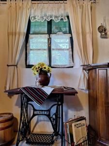 a table with a vase of flowers on top of a window at Căsuța cu Prispă in Sîncraiu +10 photos