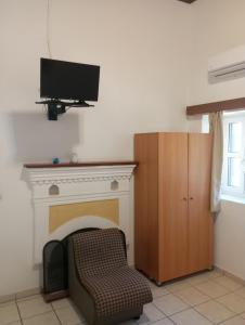 een woonkamer met een tv en een stoel bij Paradisos Kastellorizou in Meyisti