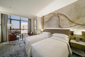 a hotel room with three beds and a wall at Rotana Al Manakha Madinah in Al Madinah +56 photos
