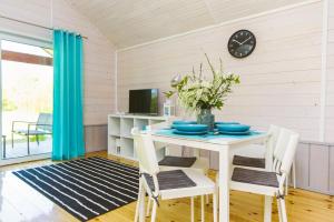 Un comedor con una mesa y sillas y un reloj. en Surf Domki Habenda z sauną ogrodową, en Sarbsk
