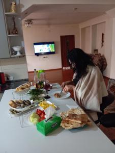 kobieta siedząca przy stole z talerzami jedzenia w obiekcie Khachik White Canyon w mieście Khachʼik