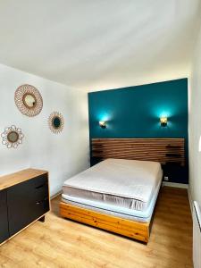 a bedroom with a bed and a blue wall at Le Paisible * * * in Aurillac