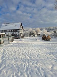 a snow covered field with a barn in the background at Szachulcowa Zagroda in Ustka