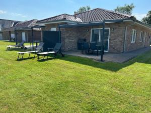 a patio with chairs and tables in a yard at Seeufer in Walchum