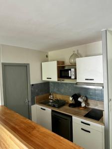 a kitchen with white cabinets and a counter top at Le Paisible * * * in Aurillac