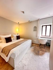 una camera con un grande letto e una sedia di AlliOli Boutique Hotel Spa a Castelló d'Empúries