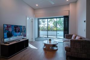 a living room with a tv and a couch and a table at Utopia Apartments by Serain Residences in Brisbane