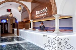 un hombre de pie en un bar en el vestíbulo de un hotel en Barceló Isla Canela, en Isla Canela