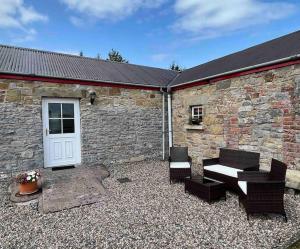 a patio with two chairs and a white door and a building at Derryvree Farm Cottage in Maguires Bridge