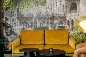 a yellow couch in a room with a wall mural at Motel One Madrid-Plaza de España in Madrid