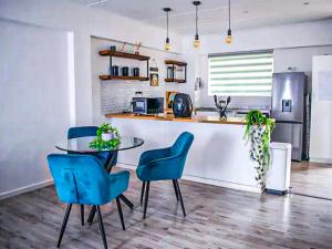 a kitchen with a table and some blue chairs at 2 Bedroom Apartment with Modern Finishes Hill Tud Stays in Pietermaritzburg