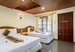a bedroom with two beds and a window at Neptune's Villa in Haad Rin