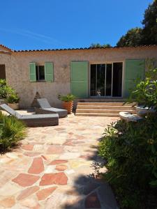 un patio con puertas verdes y una casa en Gîte Acellu, en Bonifacio