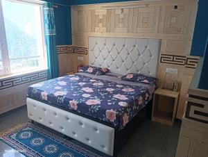 a bedroom with a bed with a blue wall at Wanderers Homestay -All mountain facing rooms in Kalpa