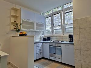 a white kitchen with white cabinets and windows at Apartment Anka in Omiš +26 photos