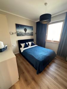 une chambre avec un lit avec une couette bleue et une fenêtre dans l'établissement Marina Blue-Apartament przy promenadzie, à Ełk