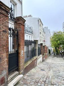 a brick building with a gate on a street at 1562 - Cosy Montmartre in Paris Olympic Games 2024 in Paris