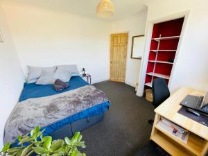 a bedroom with a bed and a desk with a laptop at Rose House, with garden, ideal for couples and families with easy parking in Kent