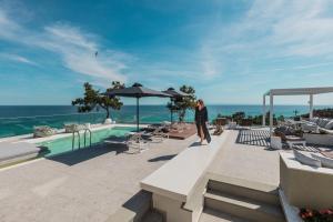 a woman standing on a bench next to a pool at 360ᵒ Luxury View Collection - Adults Only in Limenaria
