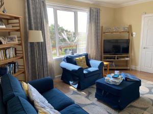 una sala de estar con muebles azules y una gran ventana. en Tigh-na-Greine en Carloway