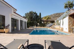 a swimming pool with chairs and a house at Grand Apollon Villa in Sounio