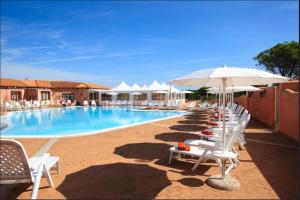 a swimming pool with white lounge chairs and an umbrella at Relaxing Residence Baia dei Mirti B4-1 Bedroom Apartment sleeps 4 persons in Vignola Mare