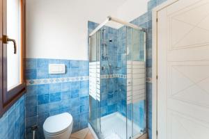 a blue tiled bathroom with a toilet and a shower at Relaxing Residence Baia dei Mirti B4-1 Bedroom Apartment sleeps 4 persons in Vignola Mare +8 photos
