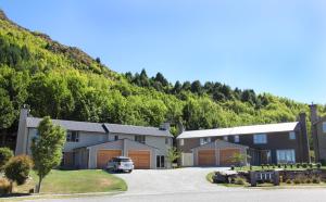 un bâtiment avec une voiture garée devant une montagne dans l'établissement Arrowfield Apartments, à Arrowtown