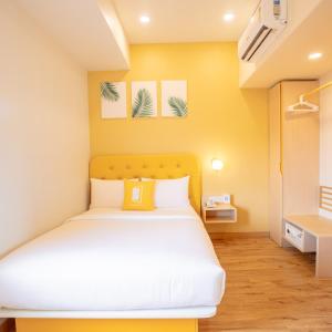 a bedroom with a bed with a yellow wall at Bloom Hotel - HSR Layout Sec 6 in Bengaluru