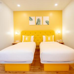 two beds in a hotel room with yellow walls at Bloom Hotel - HSR Layout Sec 6 in Bengaluru