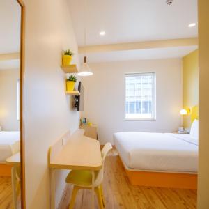 a bedroom with two beds and a desk and a mirror at Bloom Hotel - HSR Layout Sec 6 in Bengaluru